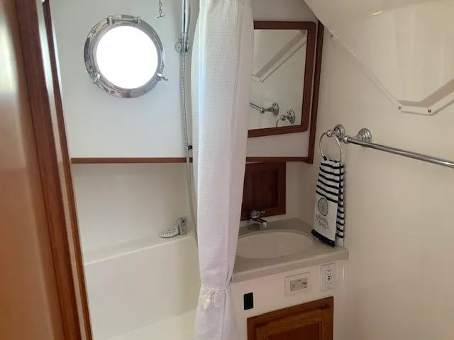 Slide: The Image of Bathroom interior of 2010 Nordic Tug 32 with porthole, sink, and shower curtain. - 35