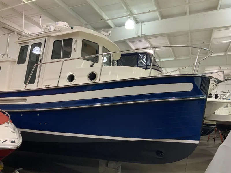 Slide: The Image of 2010 Nordic Tug 32 boat with blue hull in indoor showroom. - 5