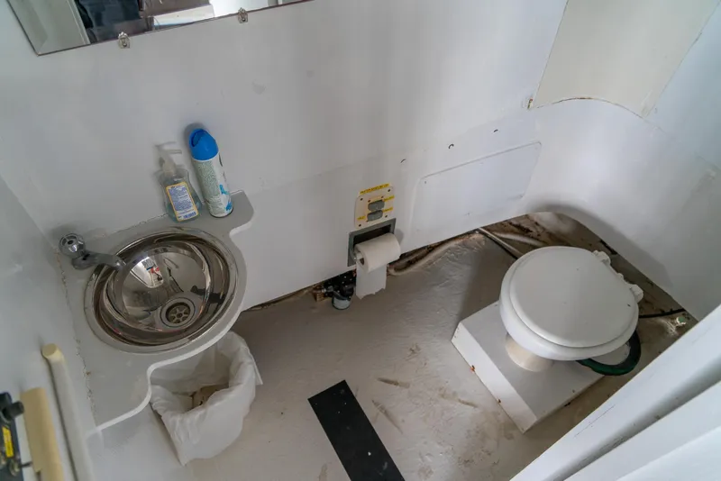Slide: The Image of 2004 Custom 40' Navy Boat bathroom with sink, toilet, and cleaning supplies. - 12