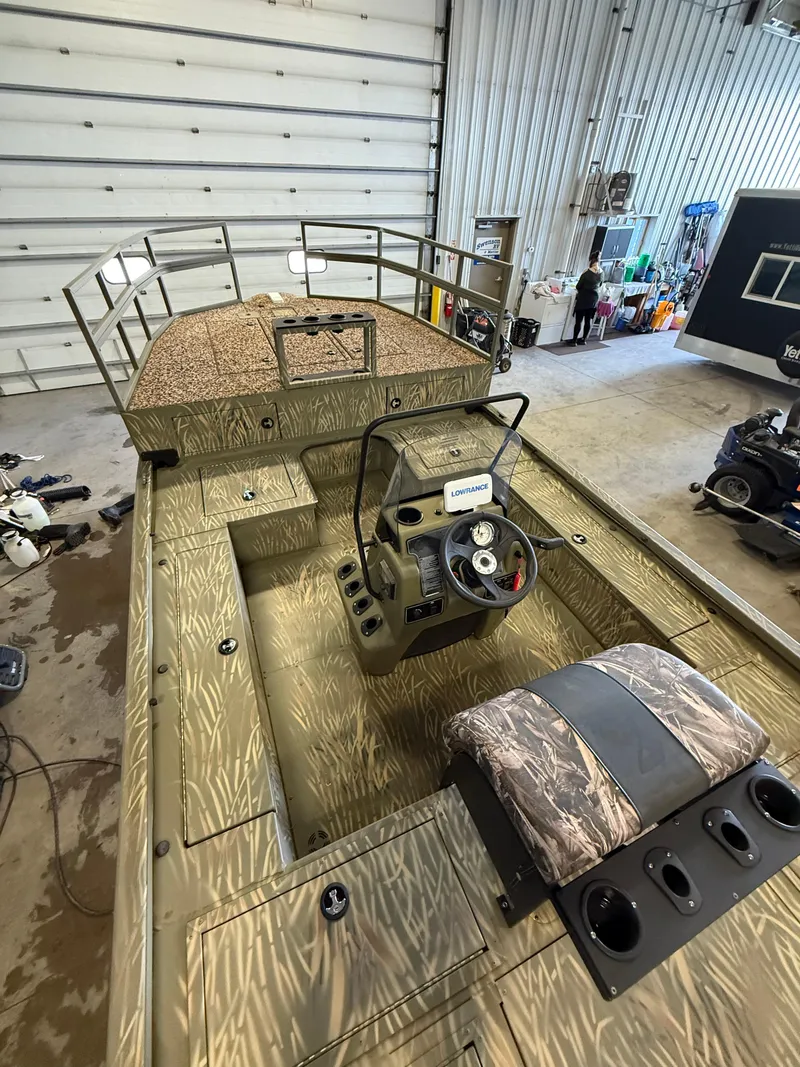 Slide: The Image of 2023 Tracker Grizzly 2072 CC Sportsman boat in a garage, featuring a camo design and steering console. - 10