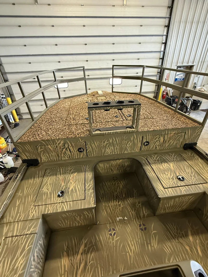 Slide: The Image of 2023 Tracker Grizzly 2072 CC Sportsman boat with camo design in a garage setting. - 12