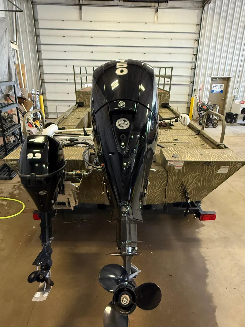 Slide: The Image of 2023 Tracker Grizzly 2072 CC Sportsman boat with dual outboard motors in a garage. - 4