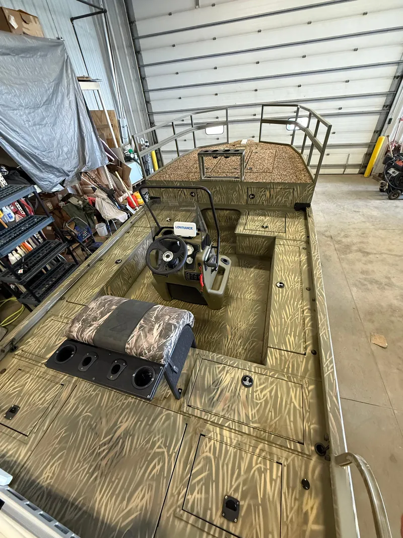 Slide: The Image of 2023 Tracker Grizzly 2072 CC Sportsman boat in a garage, featuring camouflage design. - 9
