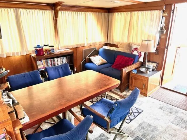 Slide: The Image of Interior of 1978 Jones-Goodell Pilothouse with dining table, blue chairs, and cozy seating area. - 19