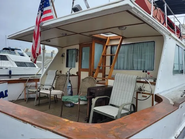 Slide: The Image of 1978 Jones-Goodell Pilothouse boat with deck chairs and American flag. - 4