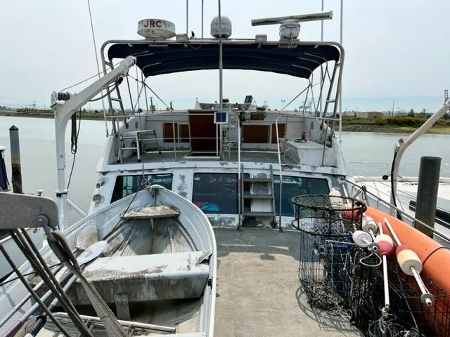 Slide: The Image of 1978 Jones-Goodell Pilothouse boat docked with fishing gear and small dinghy. - 6