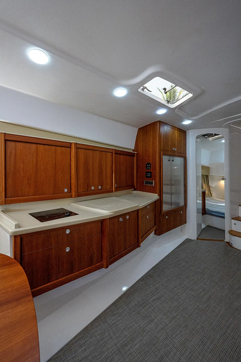 Slide: The Image of 2014 Intrepid 475 Sport Yacht interior with wooden cabinetry and modern kitchen amenities. - 31