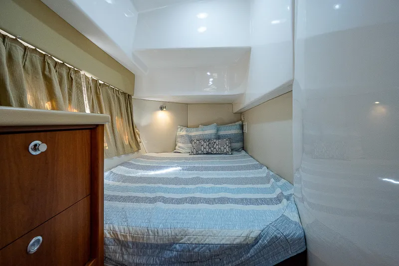 Slide: The Image of Cozy cabin interior of 2014 Intrepid 475 Sport Yacht with striped bedding and wood accents. - 40