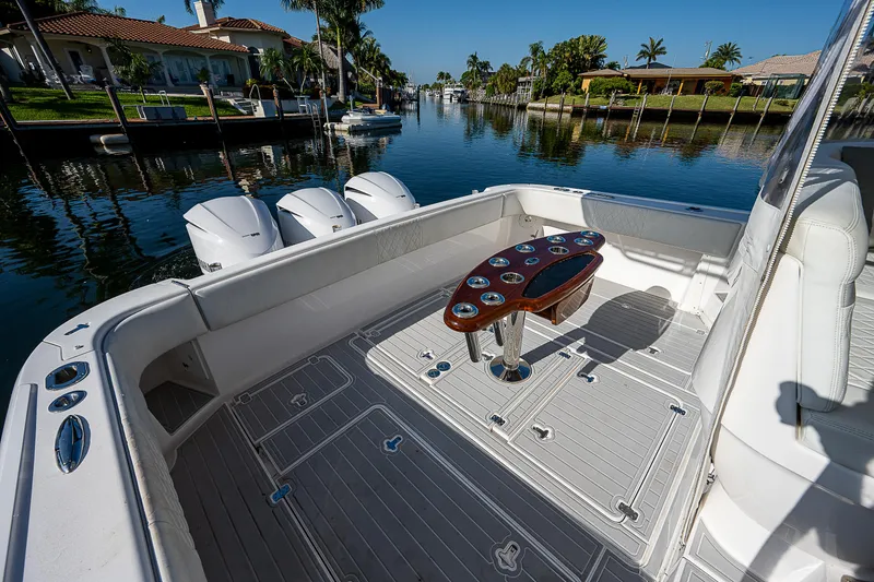 Slide: The Image of 2014 Intrepid 475 Sport Yacht deck with fishing rod holders, docked in a scenic canal. - 6