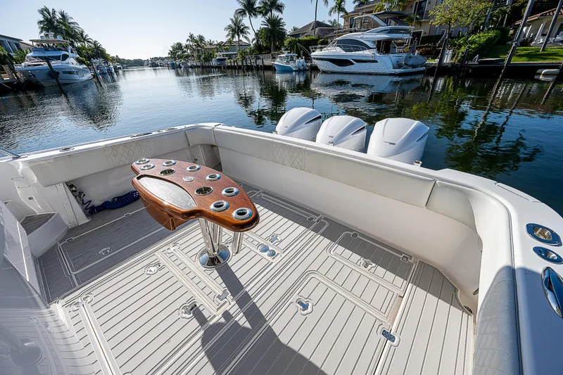 Slide: The Image of 2014 Intrepid 475 Sport Yacht deck with fishing rod holders, docked in a scenic marina. - 7