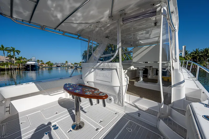 Slide: The Image of 2014 Intrepid 475 Sport Yacht deck with seating and table, overlooking a scenic waterfront. - 9