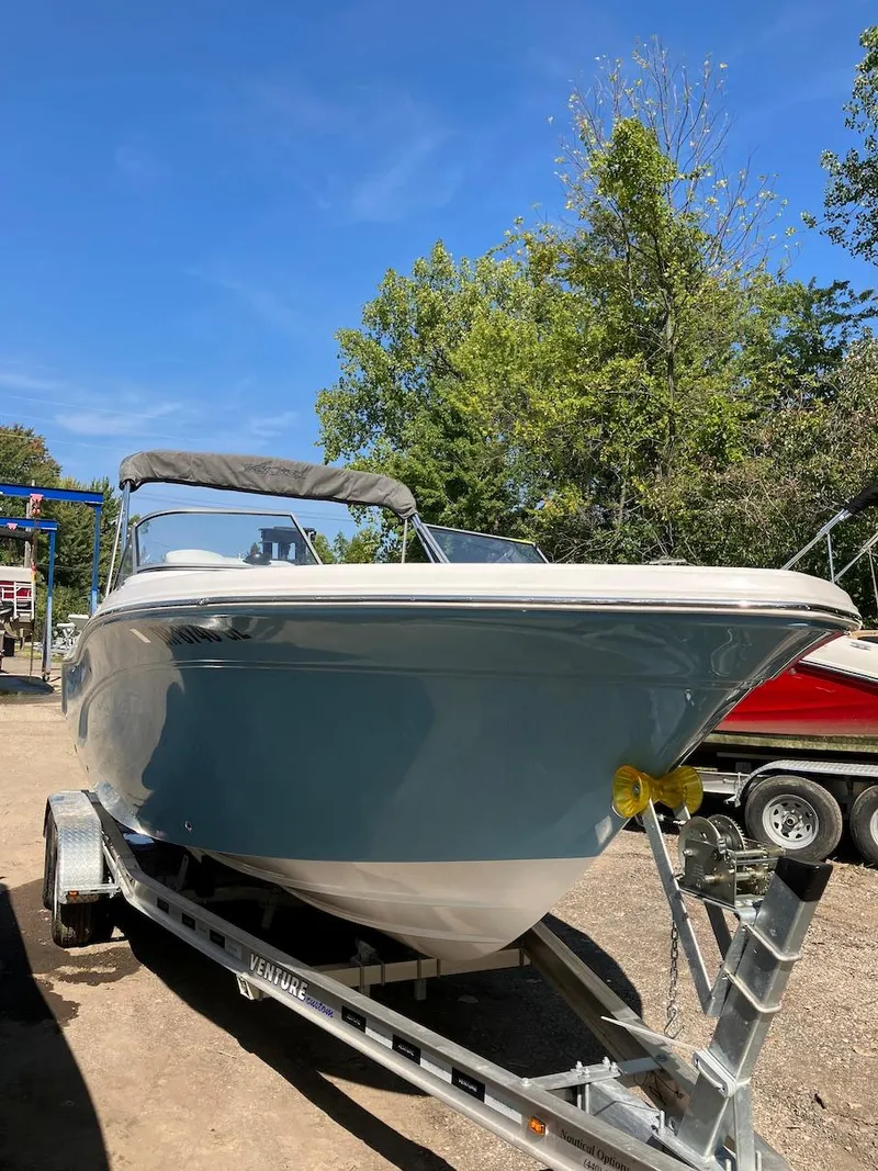 Slide: The Image of 2023 Sea Fox 226 Traveler boat on a trailer, outdoors with trees in the background. - 19