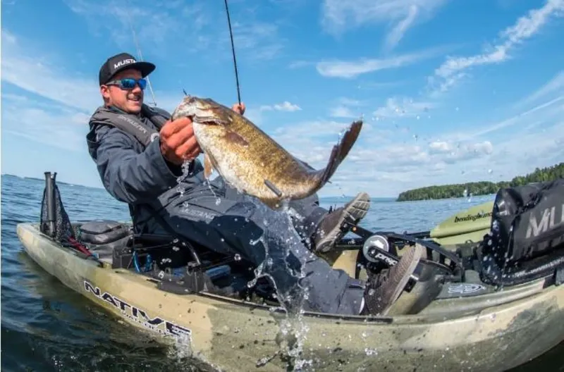 Slide: The Image of Man fishing from a 2023 Native Watercraft Titan Propel 12 kayak, holding a large fish. - 1