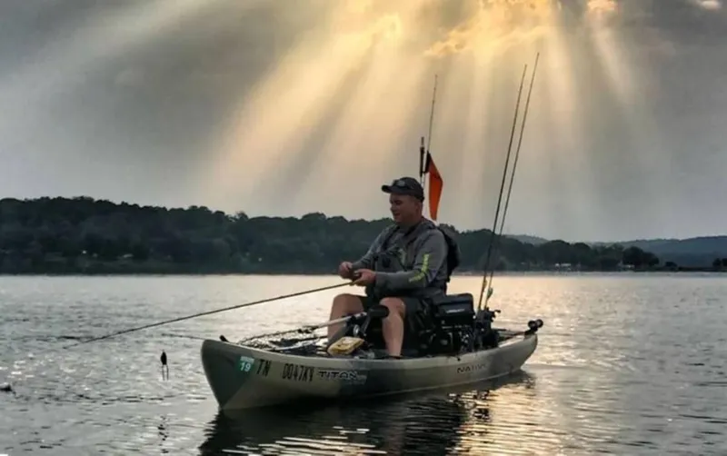 Slide: The Image of Man fishing on a 2023 Native Watercraft Titan Propel 13.5 kayak under sun rays. - 2
