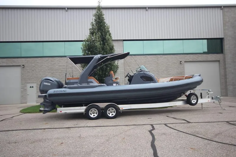The Image of 2024 Zodiac MEDLINE 9 NEO Twin 300hp boat on trailer, parked outside industrial building. - 0