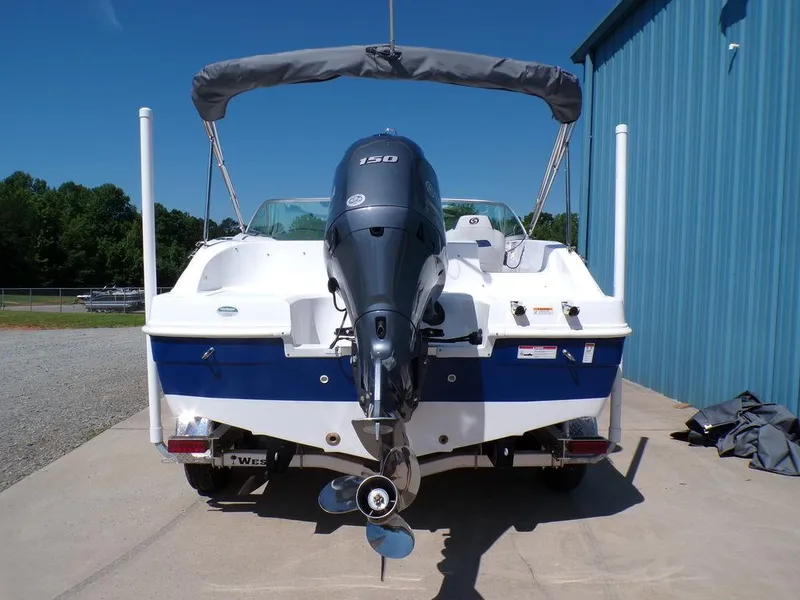 Slide: The Image of 2023 Hurricane SunDeck 187 OB boat with outboard motor, docked near a blue building. - 4
