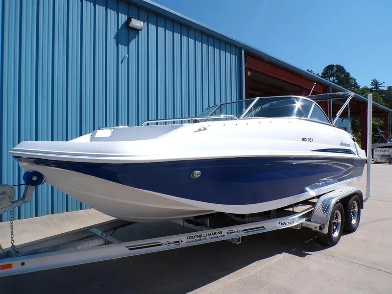 Slide: The Image of 2023 Hurricane SunDeck 187 OB boat on a trailer outside a blue building. - 6