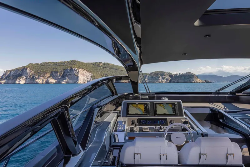 Slide: The Image of Cockpit view of 2025 Riva 68' DIABLE yacht with scenic coastal backdrop. - 14