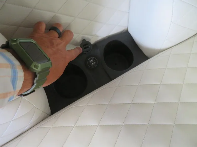 Slide: The Image of Hand adjusting cup holder on 2023 Starcraft SX 25 Q boat with white quilted seats. - 8