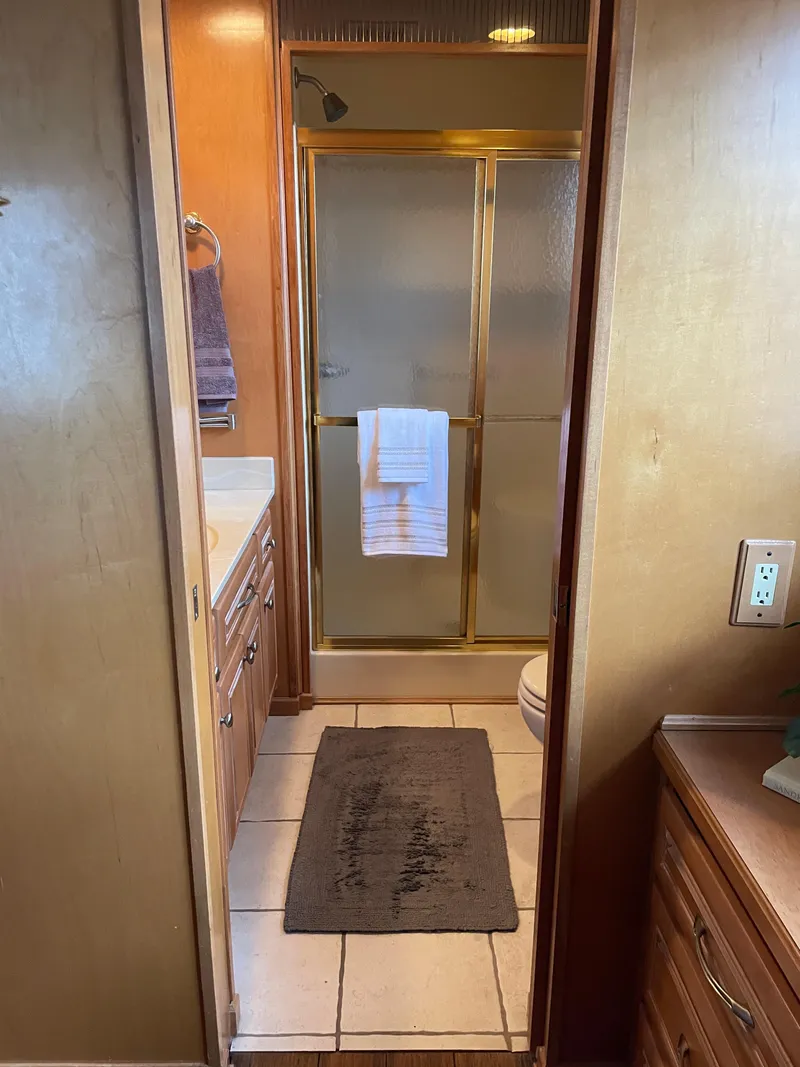 Slide: The Image of 2002 Stardust Cruisers houseboat bathroom with shower, vanity, and brown decor. - 10