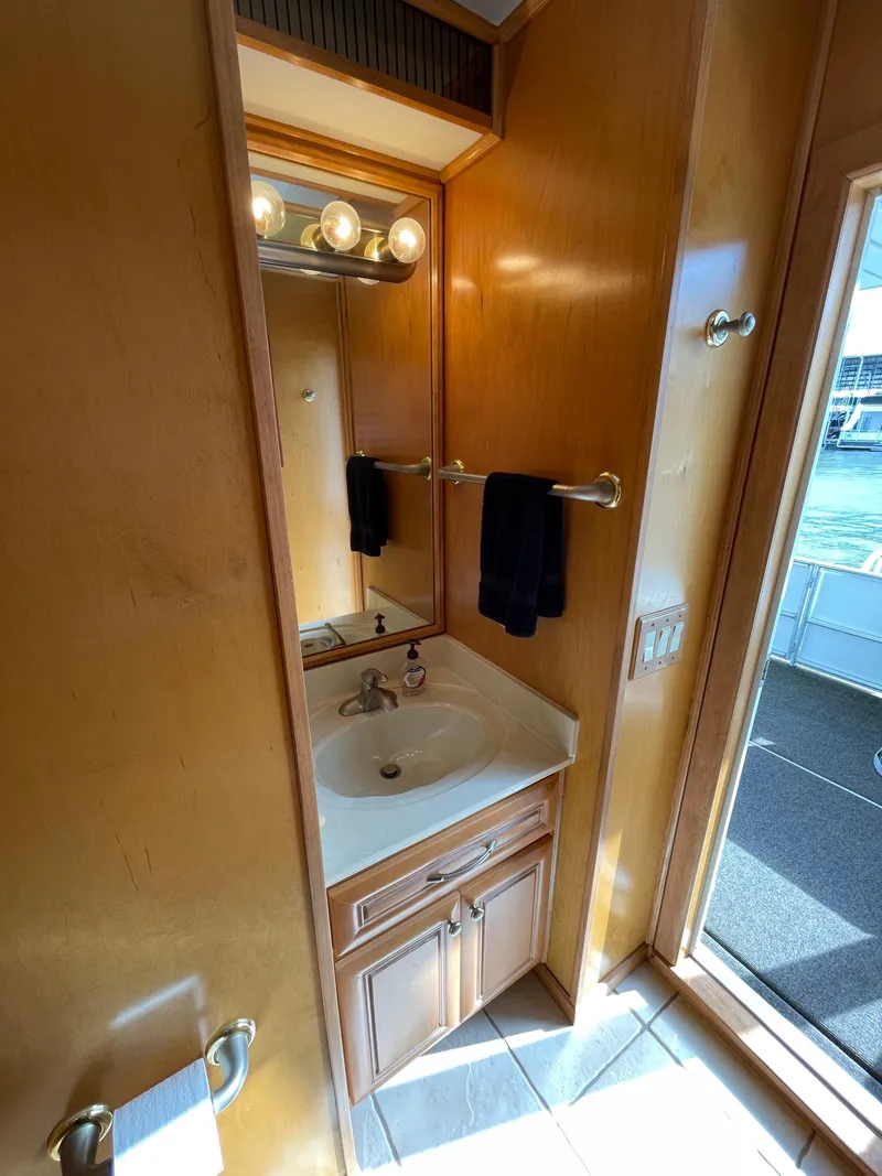 Slide: The Image of 2002 Stardust Cruisers Houseboat bathroom with sink, mirror, and wooden cabinetry. - 22