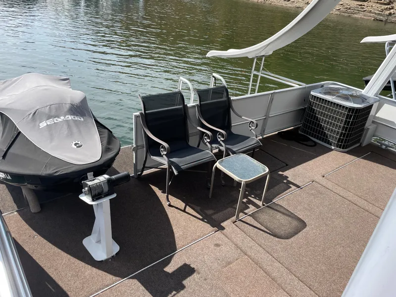 Slide: The Image of 2002 Stardust Cruisers houseboat deck with chairs, table, and covered Sea-Doo jet ski. - 23