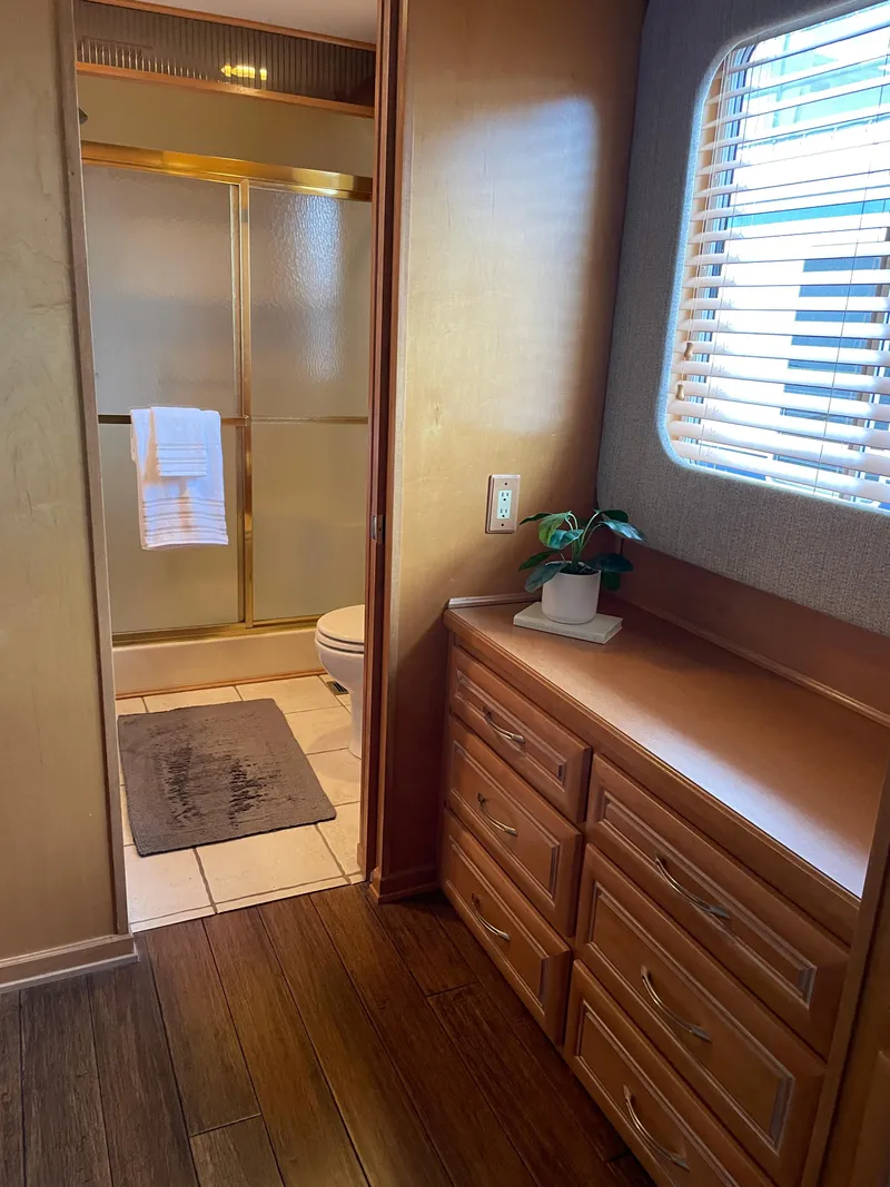 Slide: The Image of 2002 Stardust Cruisers houseboat interior with bathroom, wooden cabinets, and window blinds. - 9