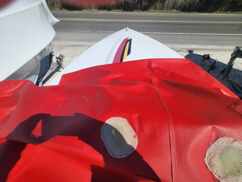 Slide: The Image of 1997 Donzi 22ZX boat with red cover, parked near a road. - 24