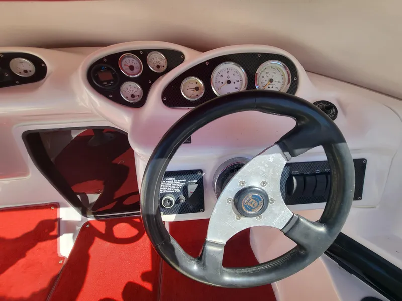 Slide: The Image of 1997 Donzi 22ZX boat dashboard with steering wheel and gauges, featuring red carpet. - 6