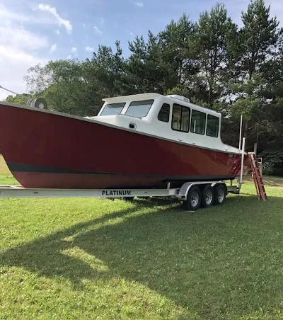 Slide: The Image of Red 2008 Gasparek Marine Eco Trawler on trailer, parked on grass with trees in background. - 2