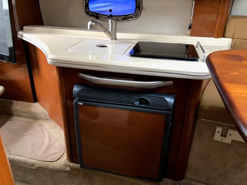 Slide: The Image of 2009 Sea Ray 270 Sundancer galley with sink, stove, and mini-fridge. - 24