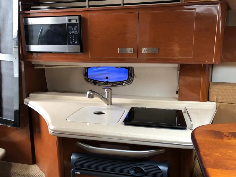 Slide: The Image of 2009 Sea Ray 270 Sundancer kitchen area with microwave, sink, and stove. - 25