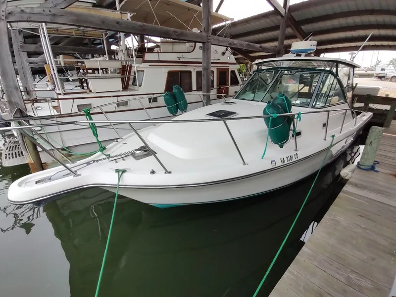 Slide: The Image of 2002 Pursuit 3000 Express boat docked in a marina under a covered shelter. - 11