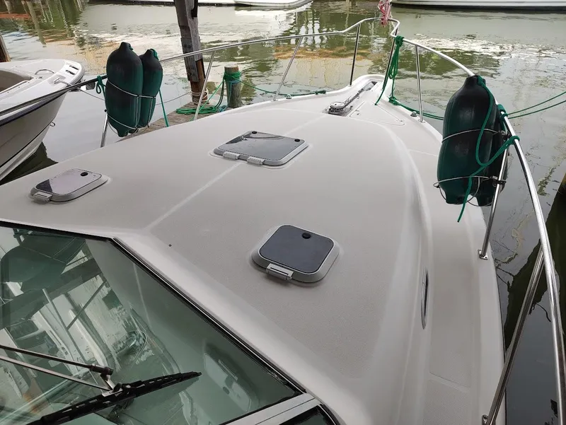 Slide: The Image of 2002 Pursuit 3000 Express boat docked, featuring deck hatches and fenders. - 13