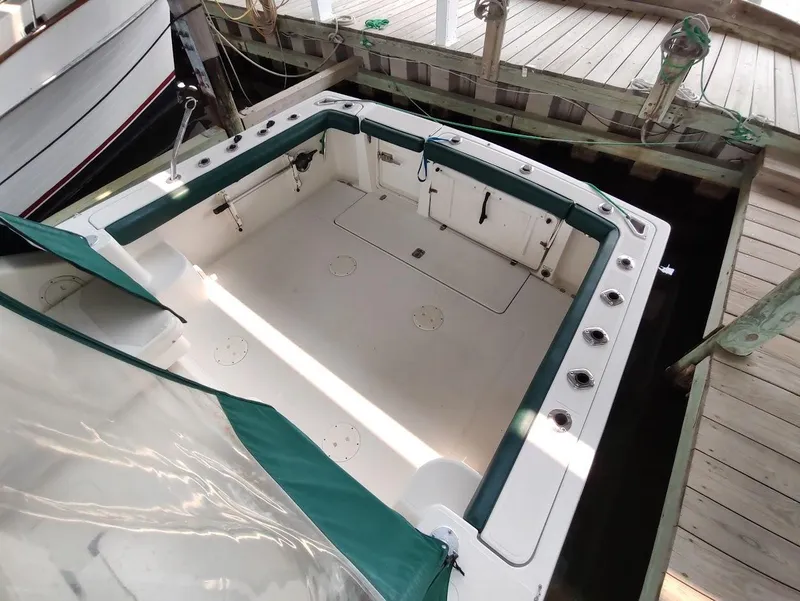 Slide: The Image of 2002 Pursuit 3000 Express boat docked, featuring spacious deck and green trim. - 19