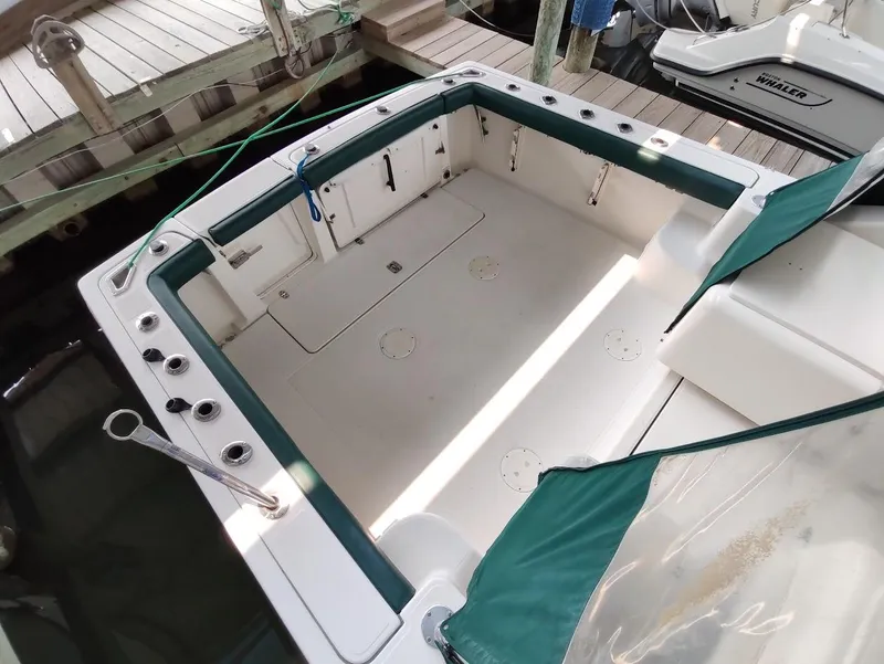 Slide: The Image of 2002 Pursuit 3000 Express boat deck with green trim, docked at a marina. - 20