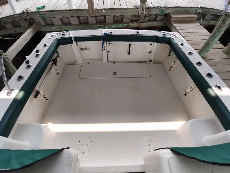 Slide: The Image of 2002 Pursuit 3000 Express boat deck with green trim, docked at a wooden pier. - 21