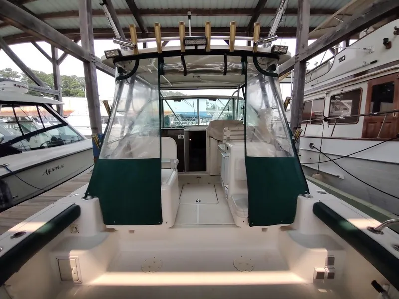 Slide: The Image of 2002 Pursuit 3000 Express boat docked, featuring a spacious cockpit and protective canopy. - 28