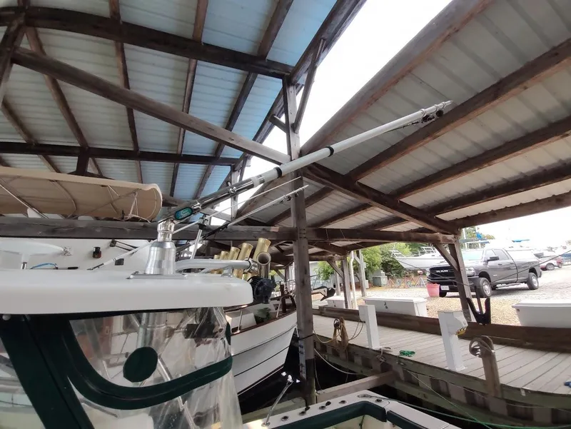 Slide: The Image of 2002 Pursuit 3000 Express boat docked under a covered marina. - 32