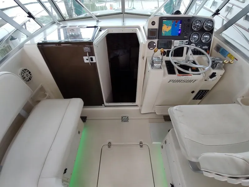 Slide: The Image of 2002 Pursuit 3000 Express boat cockpit with steering wheel, navigation controls, and seating. - 34