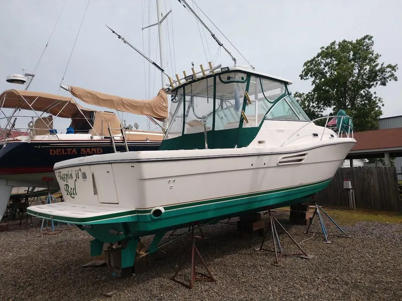 Slide: The Image of 2002 Pursuit 3000 Express boat on stands, with green trim and fishing rods. - 4