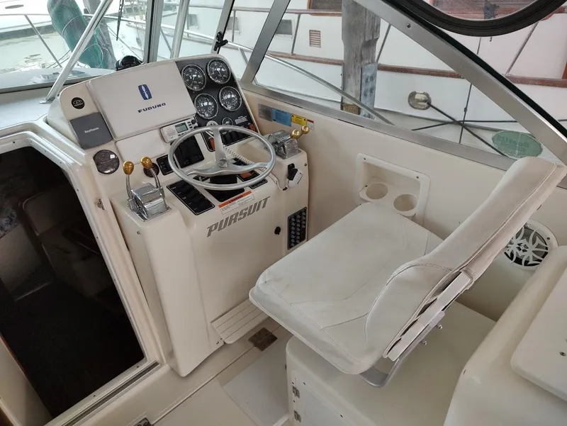 Slide: The Image of 2002 Pursuit 3000 Express boat helm with steering wheel and control panel. - 41