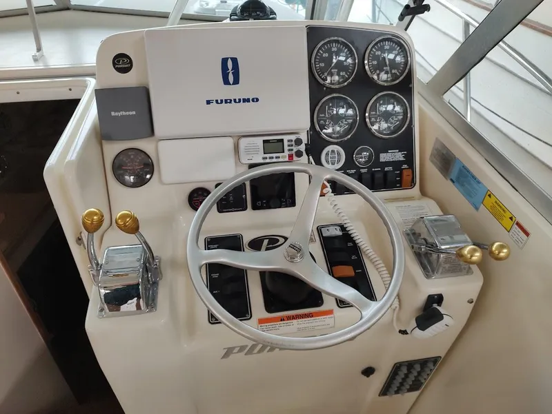 Slide: The Image of Control panel of a 2002 Pursuit 3000 Express boat with steering wheel and gauges. - 42