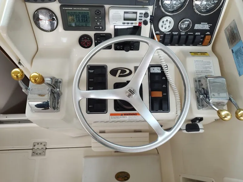 Slide: The Image of 2002 Pursuit 3000 Express boat dashboard with steering wheel and control panel. - 44