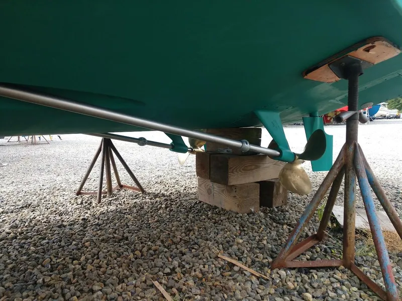 Slide: The Image of 2002 Pursuit 3000 Express boat propeller and shaft on stands, gravel ground. - 5