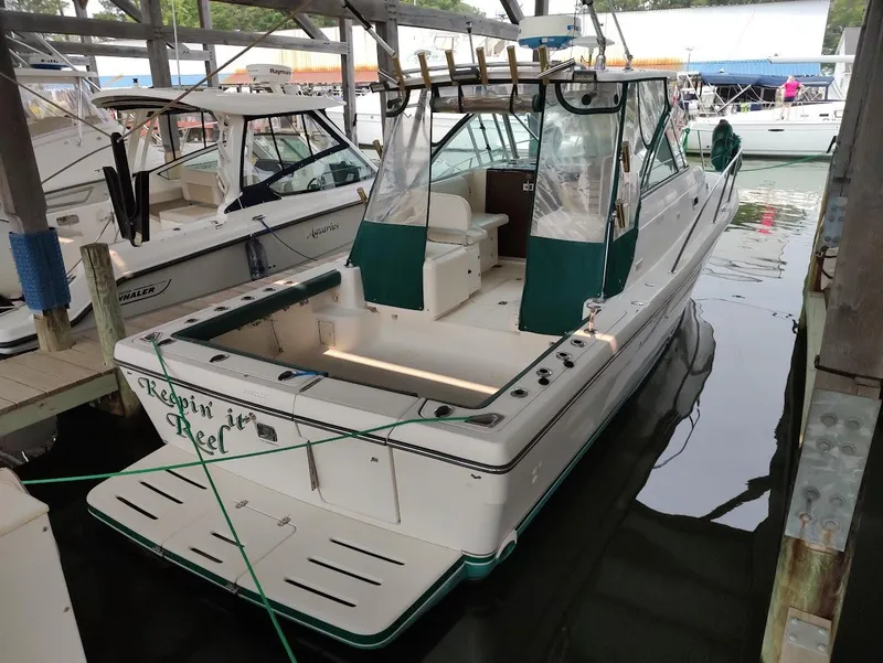 Slide: The Image of 2002 Pursuit 3000 Express boat docked in marina, featuring green accents and fishing equipment. - 9