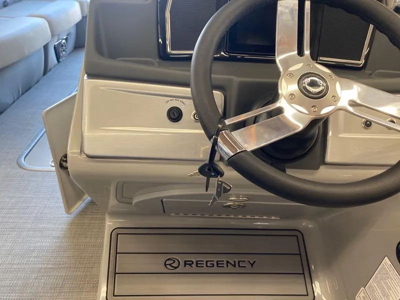Slide: The Image of 2023 Regency 250 LE3 Sport boat steering console with logo and key. - 14