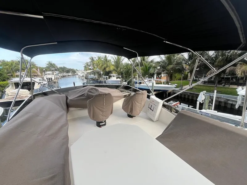 Slide: The Image of 2017 Marquis 500 Sport Yacht deck with covered seating, docked in a scenic marina. - 18