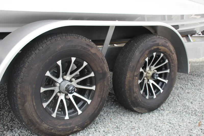 Slide: The Image of 2023 Scarab 255 Open ID trailer wheels on gravel surface. - 5