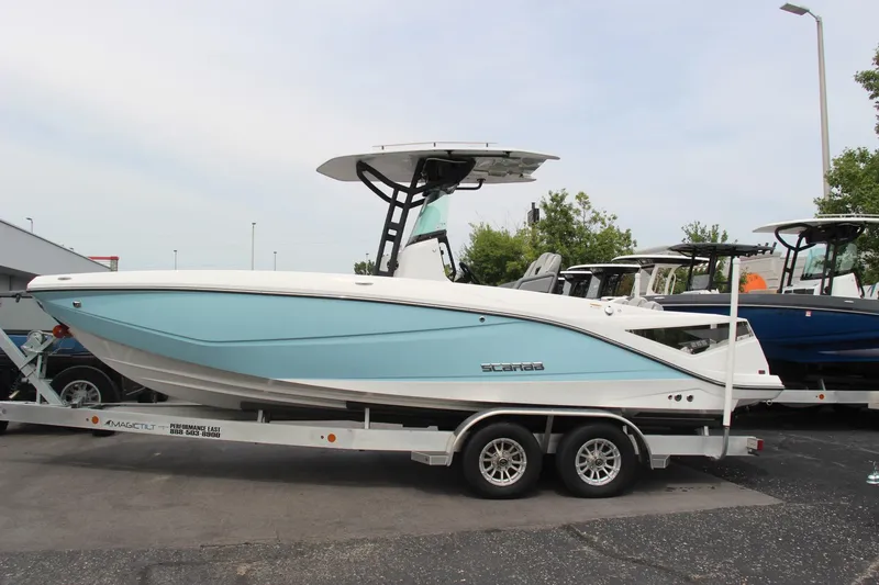 Slide: The Image of 2023 Scarab 255 Open ID boat on trailer, light blue hull, parked outdoors. - 2